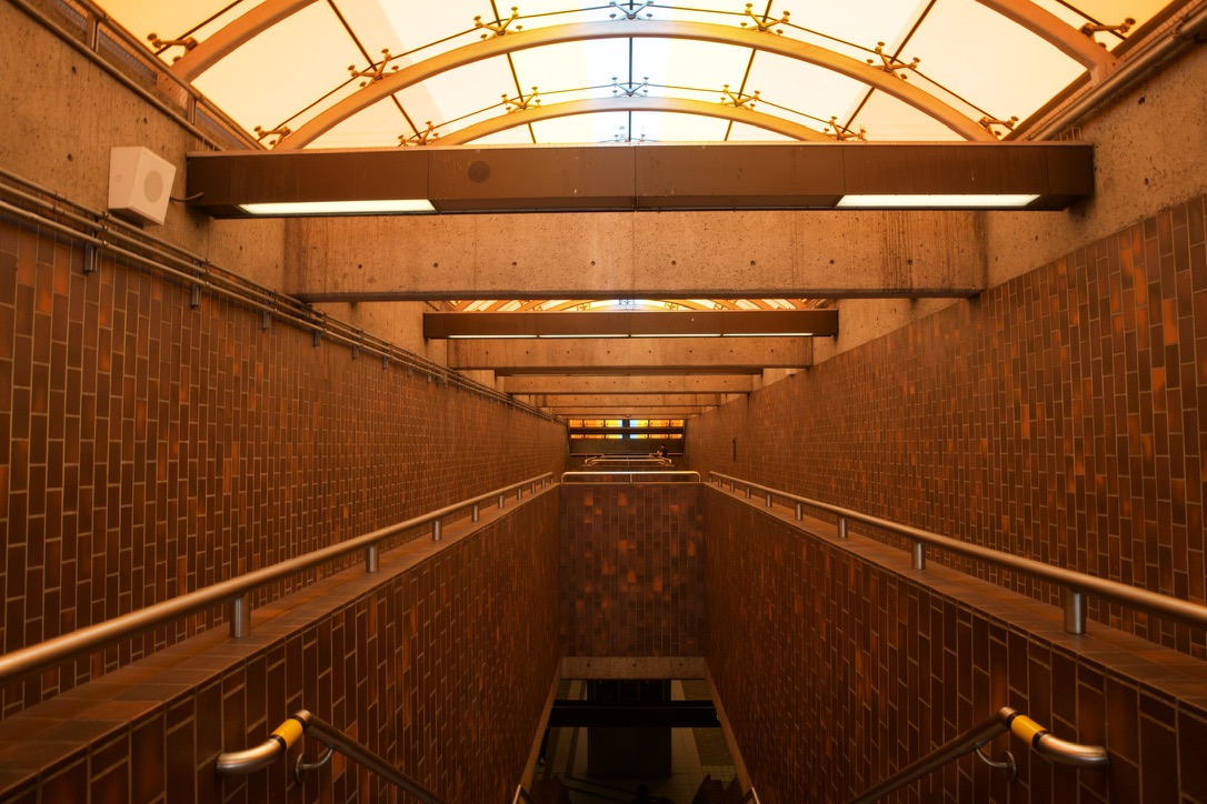 A symmetrical tiled stairwell descending through a Toronto subway station.
